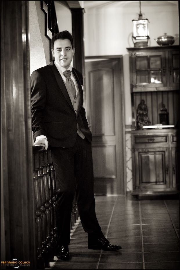 Leaning against a railing at his parents' house, the groom stands and looks ahead before leaving for the wedding ceremony in Seia in the Serra da Estrela.