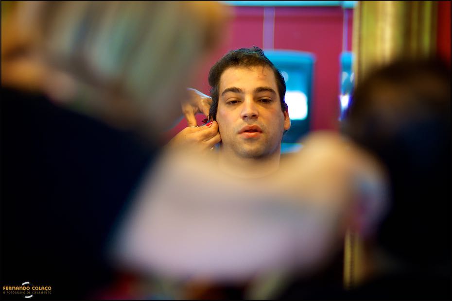 Between the blurred arms of the hairdresser, the face of the groom, very focused during the haircut for his wedding day at Quinta de Nossa Senhora da Serra in Sintra.