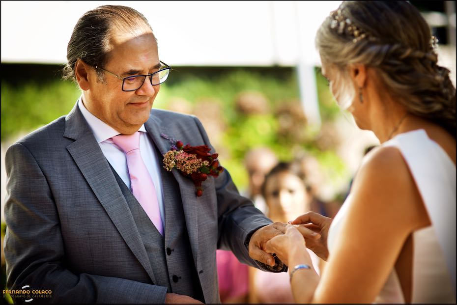 At the wedding ceremony at Quinta do Pé da Serra, the bride hands her wedding ring to the groom, as seen by the wedding photographer in Sintra.
