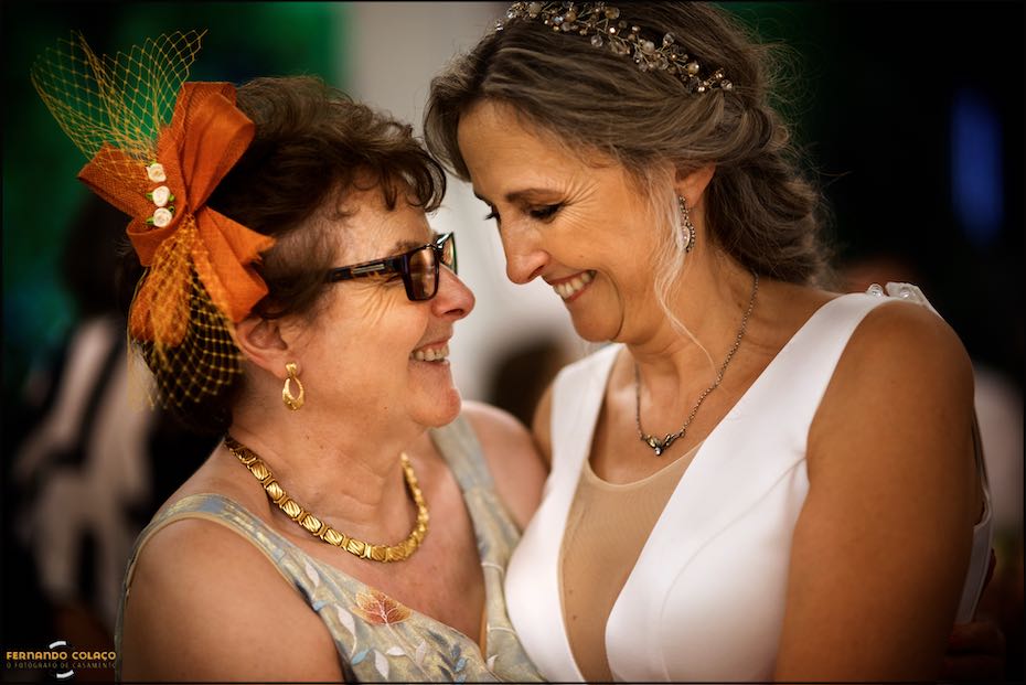 During the wedding party at Quinta do Pé da Serra in Sintra, the bride, face to face with her mother, laughs with her, as captured by the wedding photographer.